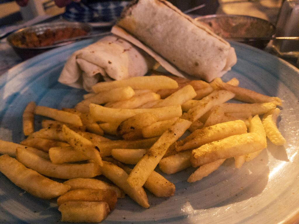 Chicken skewer wrap with mustard, caramelised onions, pickles, and chips